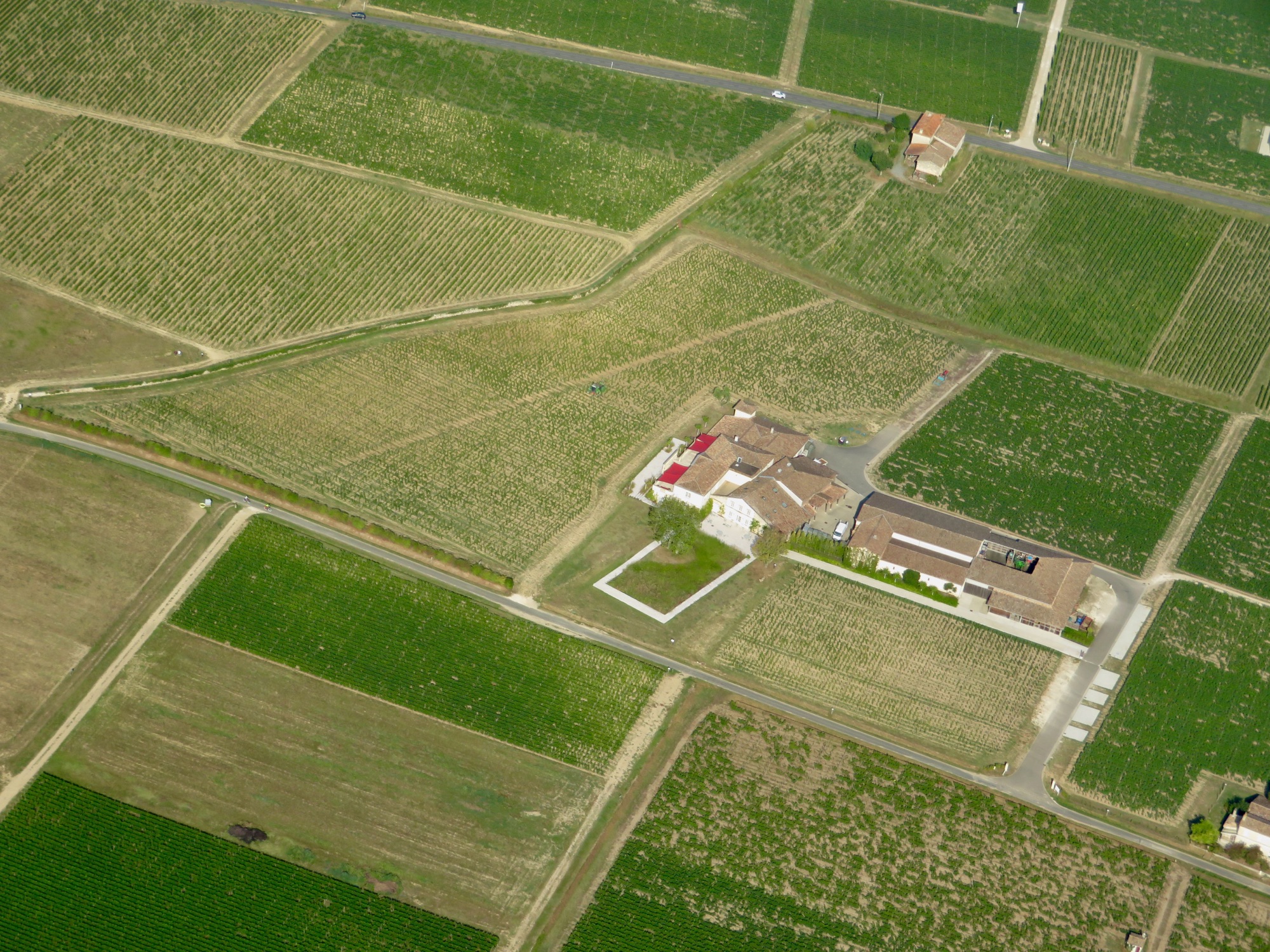 Vista aérea de una finca rodeada por parcelas agrícolas de formas geométricas